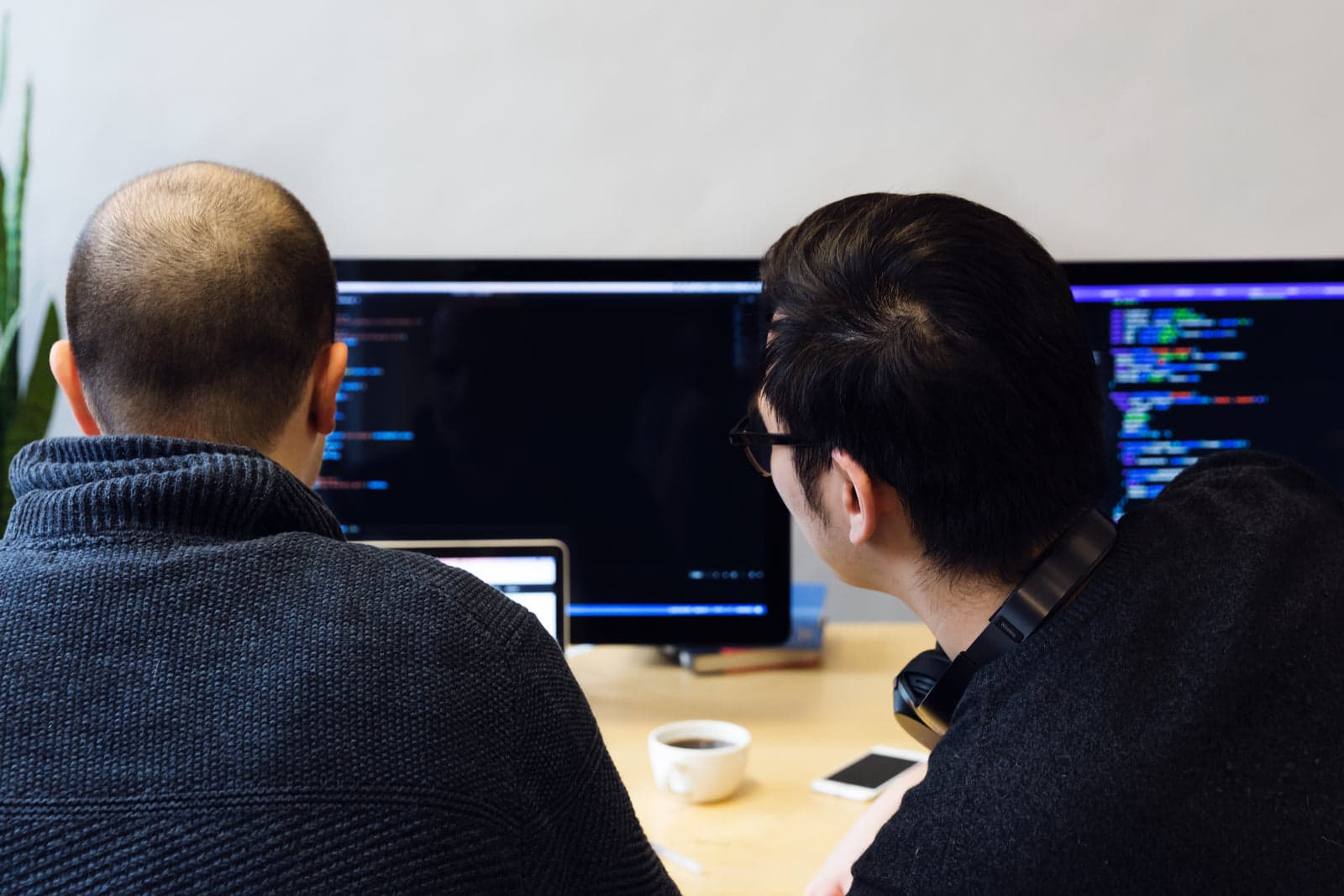 two developers reviewing code on monitors