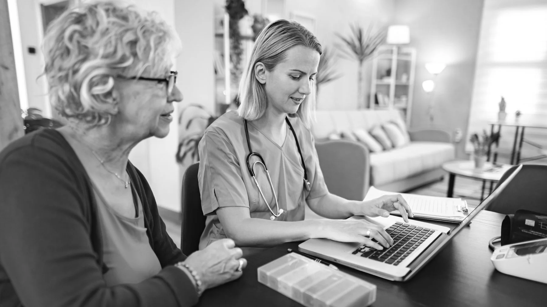 Home care nurse using a laptop with an older woman at home