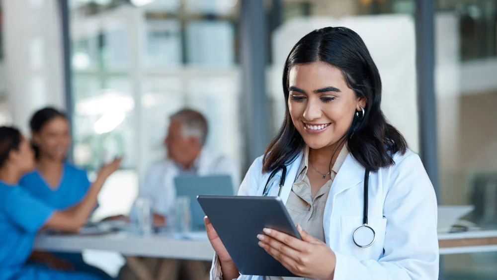 Clinician smiling while using a tablet in a care setting