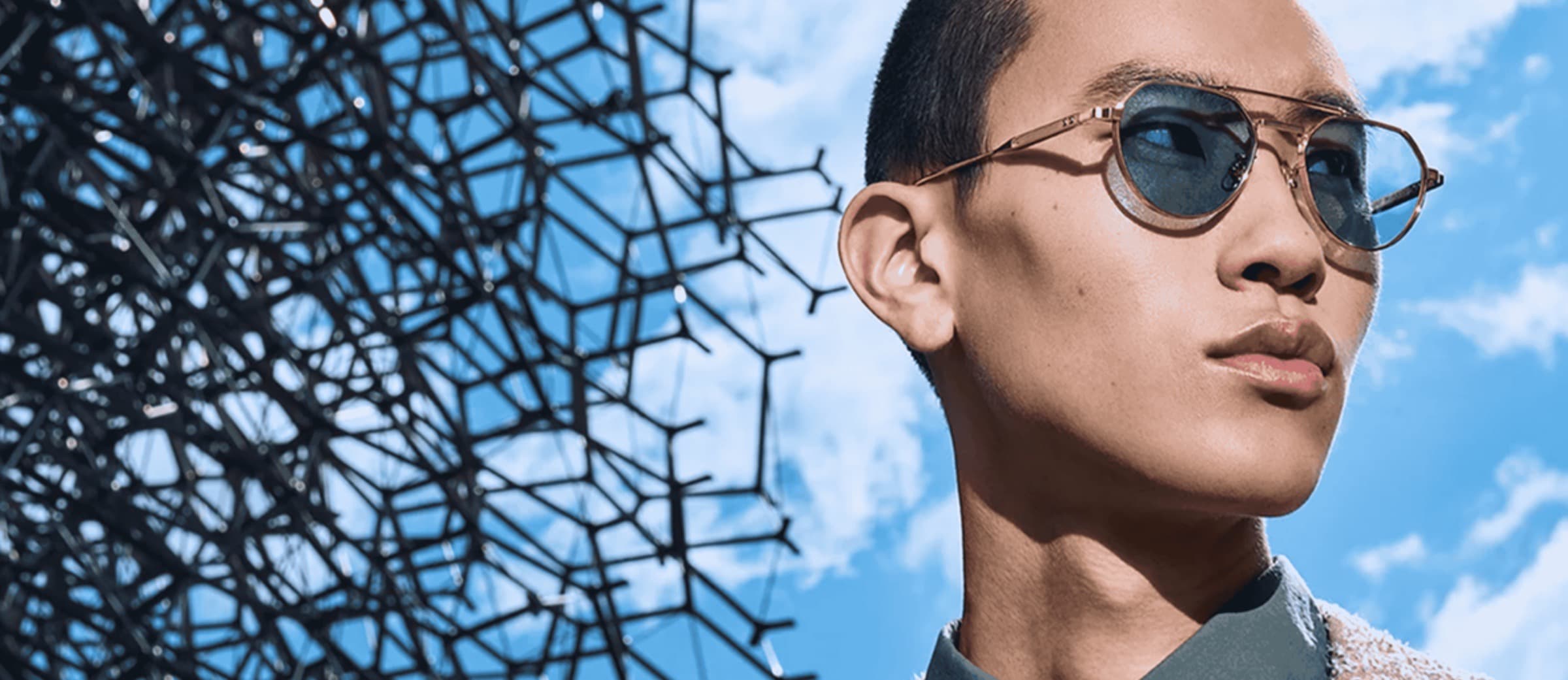 Model wearing Cutler and Gross tinted aviator sunglasses against a blue sky