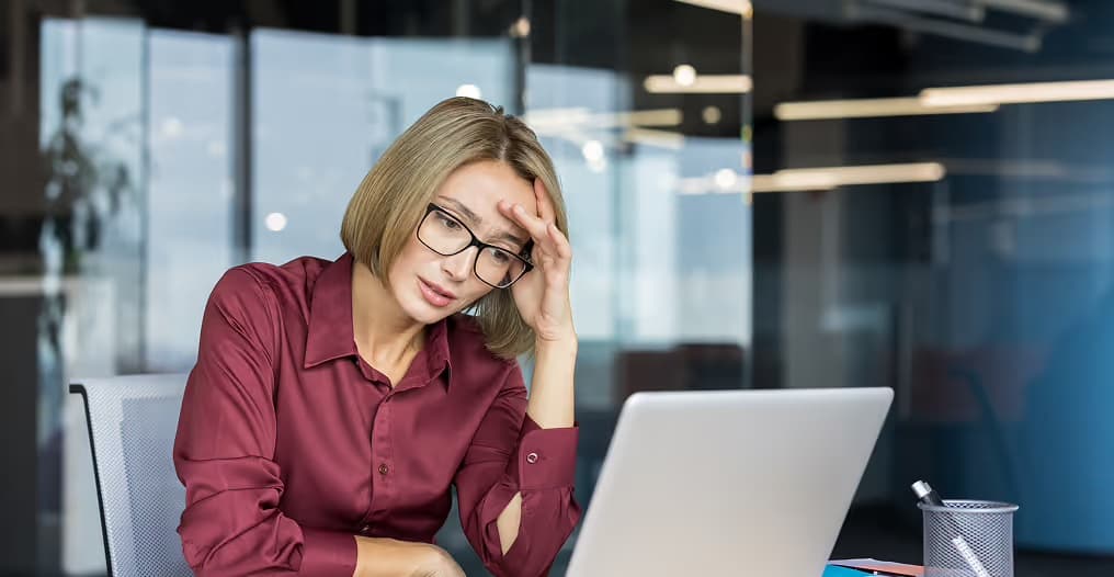 Office worker looking stressed at a laptop, illustrating the burden of manual reconciliation