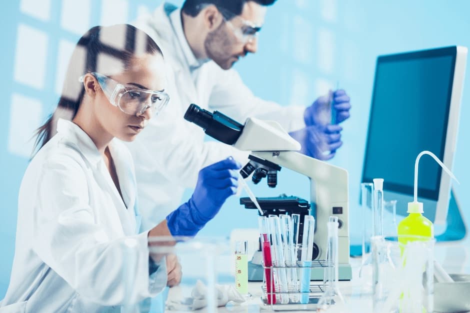 Two scientists in a laboratory working with a microscope and test tubes