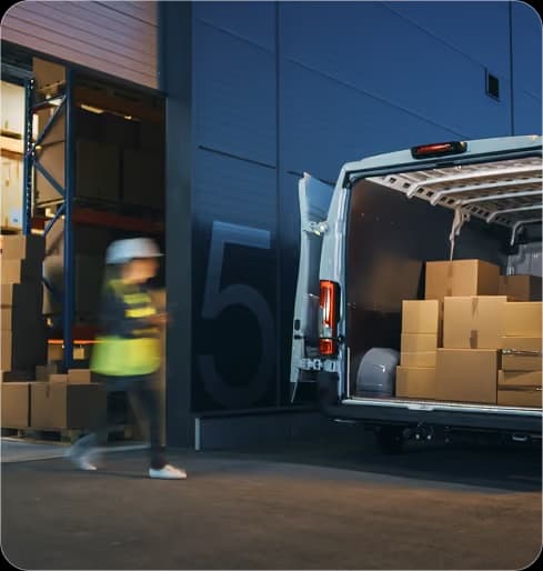 Courier loading parcels into a delivery van at dusk